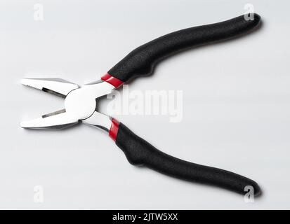 Offener Stahlpflaffer mit schwarzem Gummigriff isoliert auf Studiohintergrund Stockfoto