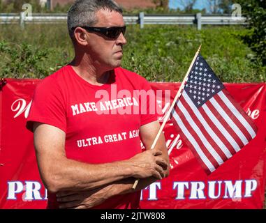 Ein Gegenproteste, der ein „Make America Ultra Great Again“-Hemd trägt, hält während des Protestes eine amerikanische Flagge. Gene Stilp, ein politischer Aktivist, der dafür bekannt ist, Requisiten zu verwenden, hielt einen Protest gegen Donald Trump in Wilkes-Barre Township ab. Trump soll hier am Samstag eine Rallye veranstalten. Die Demonstranten kamen auch heraus, um Trump zu unterstützen, schwenkten amerikanische Flaggen und trugen Trump-positive Kleidung. Stilp sprach einige Augenblicke lang und zog dann eine Flagge aus einer Tasche mit TRUMP und einem Hakenkreuz, der konföderierten Kampfflagge und einem USSR-Emblem. (Foto von Aimee Dilger/SOPA Images/Sipa USA) Stockfoto