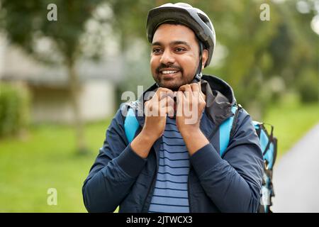 Lebensmittel Lieferung Mann Befestigung Fahrradhelm in der Stadt Stockfoto