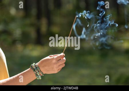 Hand mit Räucherstäbchen im Wald Stockfoto