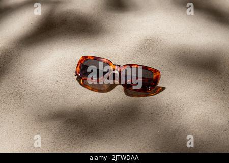 Tortoiseshell Sonnenbrille am Strand Sand Stockfoto