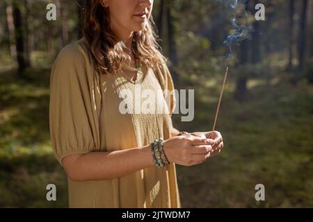 Frau mit Räucherstäbchen im Wald Stockfoto