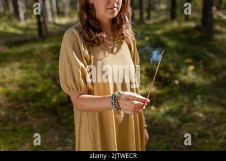 Frau mit Räucherstäbchen im Wald Stockfoto