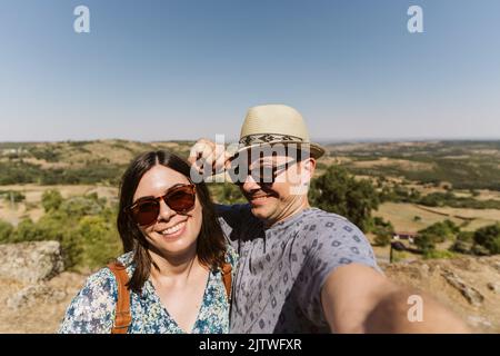 Ein wunderschönes kaukasisches Paar, das vor der Burg Trancoso mit Bergen im Rücken in Portugal steht Stockfoto