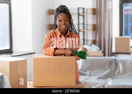 Frau mit Klebeband Verpackung Box zu Hause neu Stockfoto