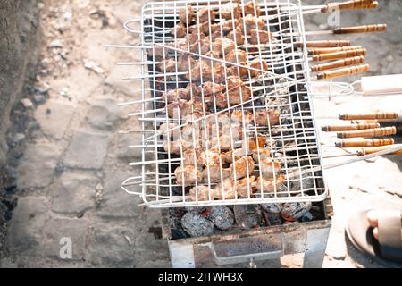 Grill wird bei einem Picknick verwendet, um Fleisch darauf zuzubereiten Stockfoto