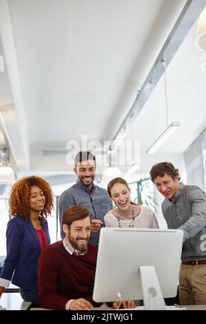 Eine weitere positive Bewertung: Eine Gruppe von Geschäftsleuten, die gemeinsam im Büro einen Computer betrachten. Stockfoto