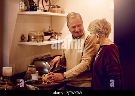 Weißt du, ich küsse mich genauso gut wie ich koche. Eine ältere Frau beobachtete ihren Mann, wie er in ihrer Küche eine Mahlzeit zubereitete. Stockfoto