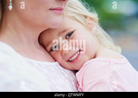 Meine Mummys die beste. Porträt eines niedlichen kleinen Mädchens, das von ihrer Mutter draußen gehalten wird. Stockfoto