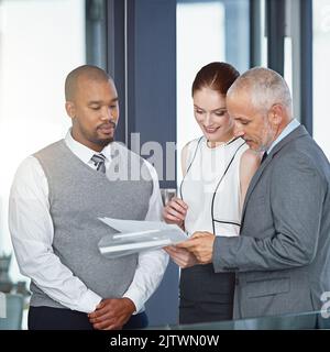 Diese sehen bisher alles in Ordnung aus. Eine Gruppe von Geschäftsleuten, die gemeinsam in einem Büro einige Papiere durchsuchten. Stockfoto