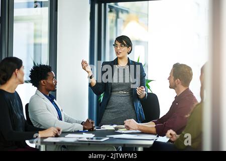 Es ist an der Zeit, sich in eine mächtige, vereinte Kraft zu verwandeln. Eine Geschäftsfrau, die ihren Mitarbeitern eine Präsentation vorstellt. Stockfoto