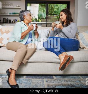 Wenn Sie nicht etwas nettes sagen können, junge Dame ... eine junge Frau und ihre Mutter, die auf dem Sofa aufholen, während sie Kaffee trinken. Stockfoto
