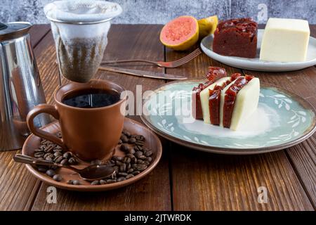 Scheiben Quark und Guava süß. Im unscharfen Vordergrund, Tuch Kaffeefilter über Tasse und Kaffeebohnen. Stockfoto