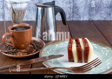 Guava-Süß- und Quark-Scheiben neben Besteck, Tasse, Bohnen und Stoffkaffee Filter Seitenansicht. Stockfoto