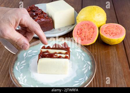 Mann, der gestapelte Scheiben Guava-Süß- und Quark aufhob Stockfoto