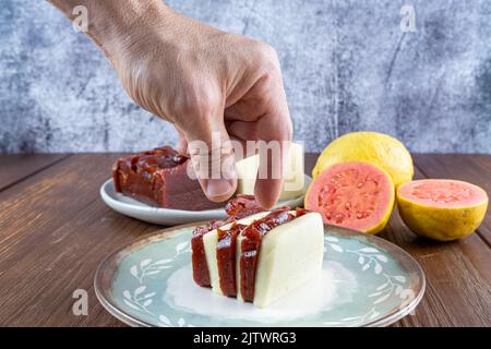 Nahaufnahme der Hand eines Mannes, der die Scheiben von Guava-Süße und Quark aufsammeln wollte. Stockfoto