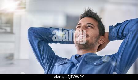 Erfolg ist etwas, worauf man stolz sein kann. Ein junger Geschäftsmann, der eine Pause von der Arbeit macht. Stockfoto