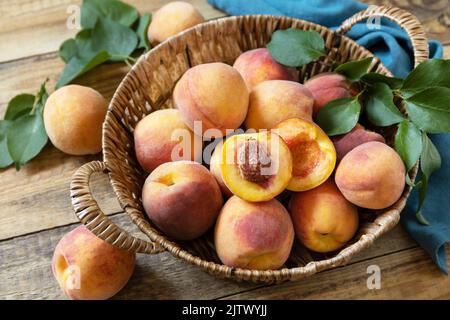 Herbsternte Hintergrund. Bio-Früchte. Bauernmarkt. Korb mit reifen Pfirsichen auf einem rustikalen Holztisch. Stockfoto