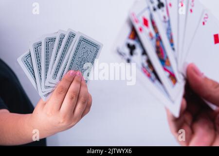 Zwei Spieler spielen Poker und heben ihre Hände. Menschen in der Mitte eines interessanten Pokerspiels. Hände mit Karten. Stockfoto