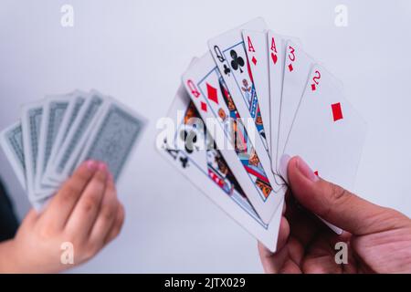 Menschen, die Poker spielen. Hände von zwei Spielern, die ihre Karten in einem Pokerspiel erhöhen. Spieler im Begriff, ein Glücksspiel zu gewinnen. Stockfoto