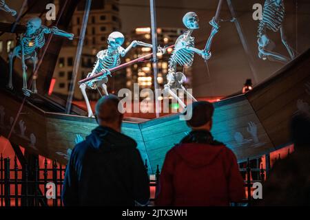 London, Großbritannien. 1.. September 2022. Charon Wheel: 32ft rotierendes Zoetrope mit Nachbildungen menschlicher Skelette an den Royal Docks im Osten Londons. Charons Radinstallation wurde im Rahmen des Greenwich+Docklands International Festivals vom amerikanischen Künstler Peter Hudson ursprünglich für das Burning man Festival entworfen. Das Rad erfordert 12 Personen, die gemeinsam arbeiten, um den mythologischen Fährmann zu drehen und zu animieren, der im griechischen Mythos die Seelen der kürzlich verstorbenen über den Fluss Styx rudert. Kredit: Guy Corbishley/Alamy Live Nachrichten Stockfoto