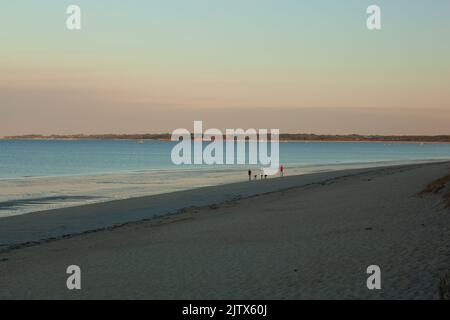Laufen und Morgenspaziergang an einem Strand bei Ebbe. Das Wetter ist ruhig, das Meer ist auch ruhig. Pastelltöne dominieren am Himmel und am Strand. Der Läufer Stockfoto