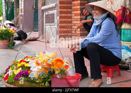 Vietnamesische Dame Floristin trägt Bambushut Verkauf von Blumen auf dem Straßenmarkt, Hai Phong, Vietnam Stockfoto