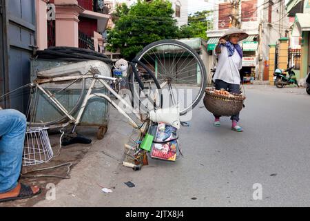 Vietnamesischer Straßenhändler mit Fahrradkörben und Fahrradreparatur auf der Straße, Hai Phong, Vietnam Stockfoto