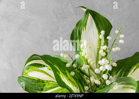 Frühlingslilie des Tales Blumenstrauß auf grauem Beton Hintergrund. Hochzeitskonzept oder Urlaubskonzept Stockfoto