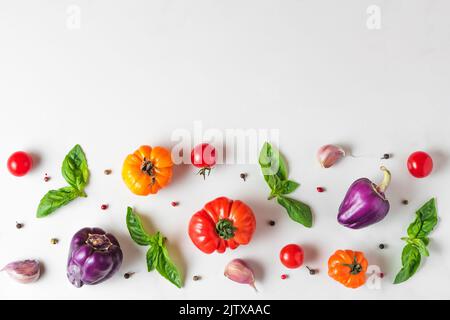 Kreatives Layout aus Tomaten, Pfeffer, Knoblauch, Basilikum. Flach liegend. Draufsicht. Lebensmittelzusammensetzung. Gemüse isoliert auf weißem Hintergrund. Lebensmittelzutaten Stockfoto