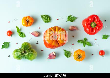 Lebensmittelzusammensetzung. Tomaten, Basilikum, Knoblauch und Pfeffer auf pastellblauem Hintergrund. Flach liegend. Draufsicht. Gemüsemuster Stockfoto