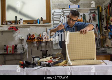 Handwerker beim Malen eines neu restaurierten alten Stuhls Stockfoto