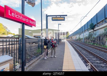 Zwei Frauen stehen auf einer Bahnhofsplattform und blicken auf ein iphone in Sydney, Australien. Straßenbahnhaltestelle Leichhardt North Stockfoto