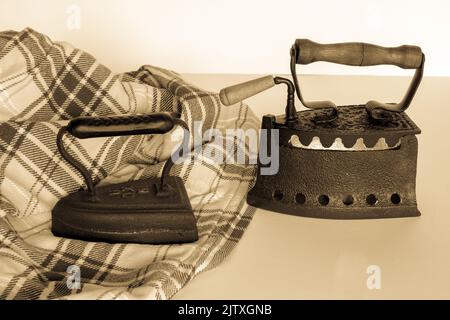 Bild von alten, kohlebefeuerten Eisen mit einem zu bügelenden Hemd. Alte Erinnerungen und Bräuche. Vintage Schwarz-Weiß-Foto Stockfoto