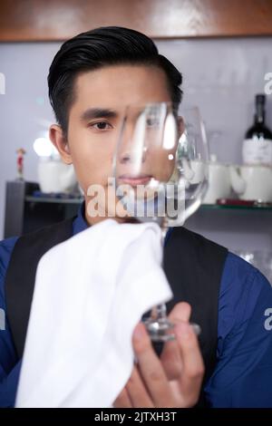 Vietnamesischer Barkeeper überprüft, ob das Glas sauber genug ist Stockfoto