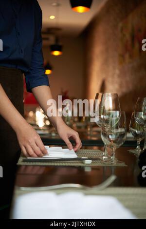 Zugeschnittenes Bild der Kellnerin, die einen Tisch für Gäste vorbereitet Stockfoto