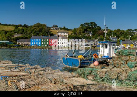 Bantry, Irland -12. August 2022: Altes Fischerboot aus Holz, Fischernetze und Krabbenfallen in der Bantry Bay mit der Innenstadt von Bantry im Hintergrund Stockfoto