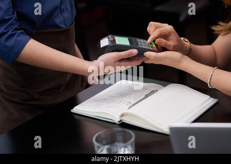 Nahaufnahme einer Frau, die einen PIN-Code eingibt, um im Restaurant zu bezahlen Stockfoto