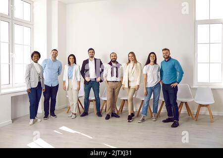 Lächelnde, multiethnische Mitarbeiter posieren gemeinsam im Büro Stockfoto