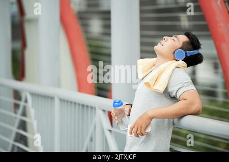 Junger asiatischer Mann müde nach dem Joggen am Morgen Stockfoto