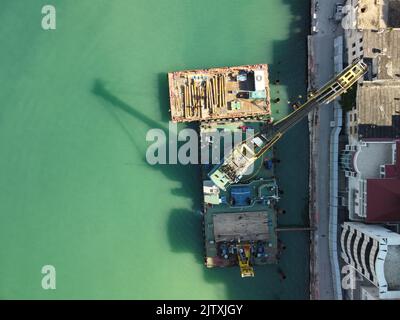 Schwimmende Kranbaggerschiffe, die am Bau einer Marina arbeiten. Luftaufnahme von oben Stockfoto