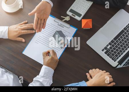 Home Sales und Home Insurance Konzept. Immobilienmakler sprach über die Bedingungen des Hauskaufvertrags und bat den Kunden, das Dokument zu unterzeichnen Stockfoto