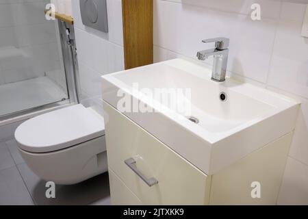 Weißes Waschbecken mit Wasserhahn und Toilettenschüssel im Badezimmer Stockfoto