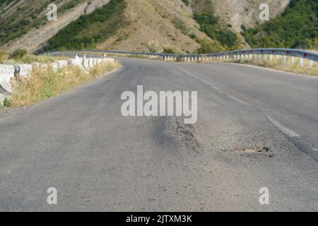 Verformte Asphaltoberfläche der Straße durch Schmelzen des Materials aufgrund von Hitze und überlasteten Lastwagen verursacht Stockfoto