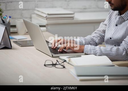 Zugeschnittenes Bild eines Geschäftsmannes, der an seinem Tisch auf einem Laptop arbeitet Stockfoto
