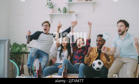 Glückliche Freunde mit argentinischen Flaggen, die gemeinsam zuhause im Fernsehen die Sportmeisterschaft verfolgen, und glücklich über den Sieg der Lieblingsmannschaft Stockfoto