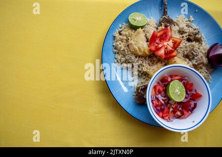 Eine Platte mit kenianischem Pilau auf gelbem Hintergrund mit einem Kopierraum. Stockfoto