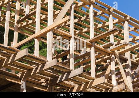 Holzhausrahmen ist im Bau, unvollendete Außenseite aus rauen Brettern und Balken Stockfoto