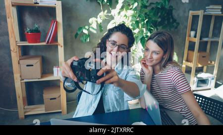 Junge kreative Designer posieren für Selfie zusammen im informellen, modernen Büro. Sie nutzen Kamera, lachen und geselligen sich. Lifestyle-Konzept für Jugendliche. Stockfoto