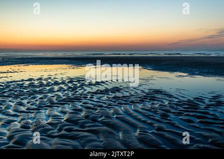 Warmer Sonnenuntergang bei Ebbe in Breskens (Zeeland, Niederlande) Stockfoto